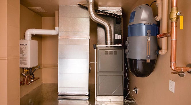 A large metallic furnace and duct system in a room.